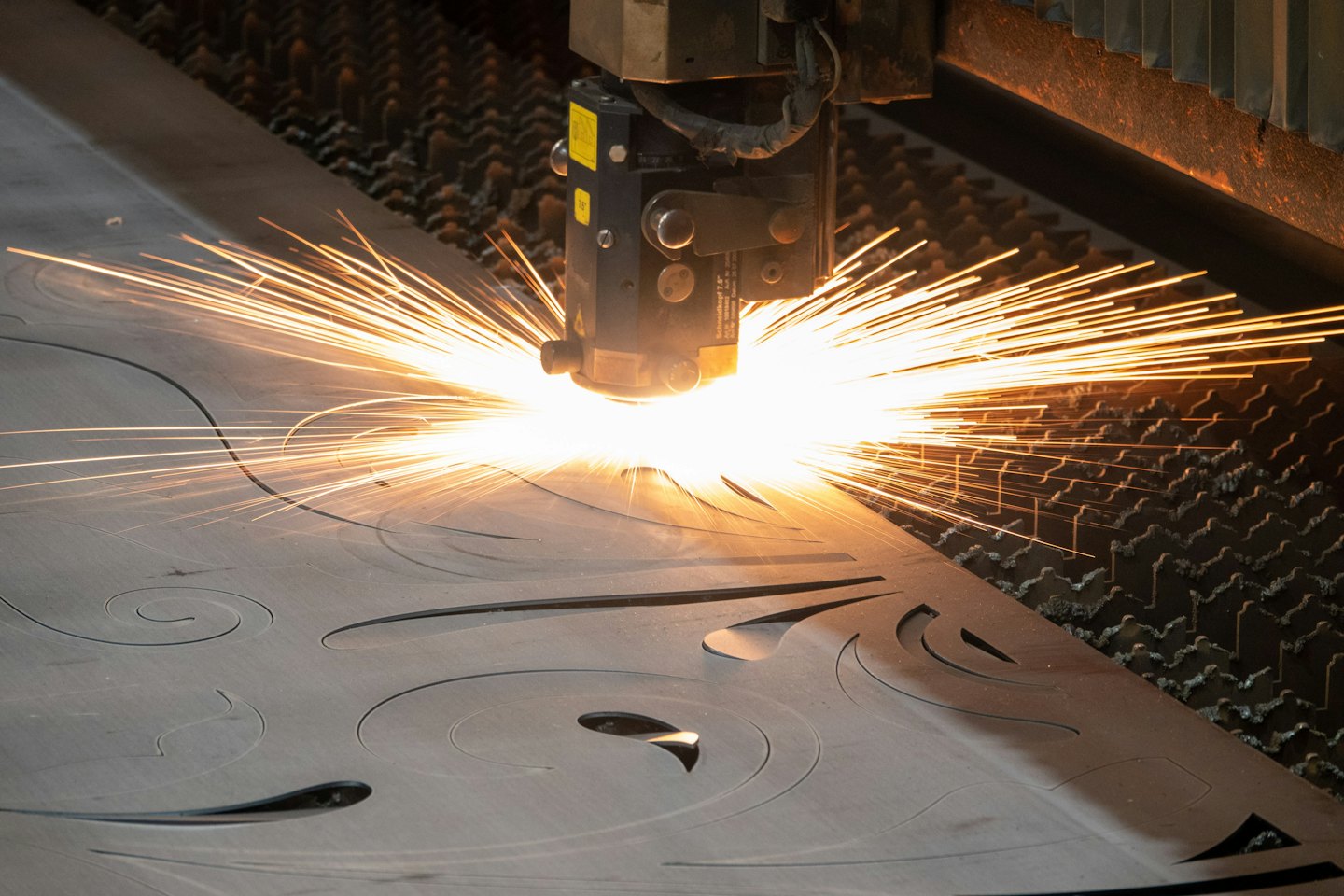Tööstuslik laserlõikur lõikab metallplaati keerulisi mustreid.